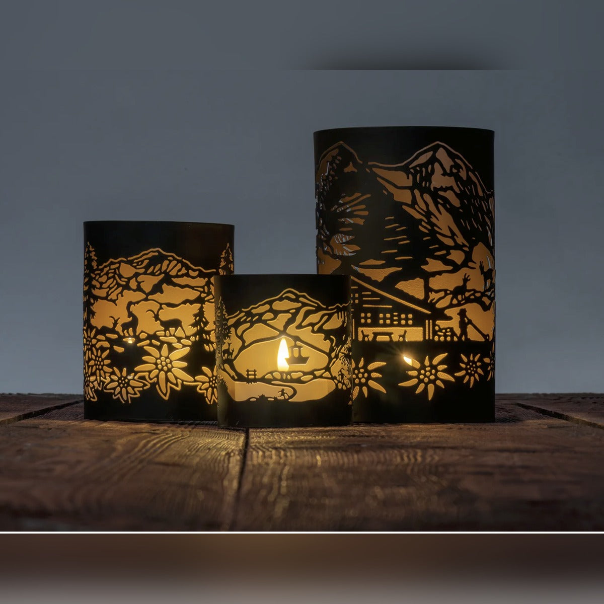Alpines Windlicht 3er Set in Schwarz/Gold mit Bergmotiven, Edelweiß und Gondel, mit Teelicht beleuchtet